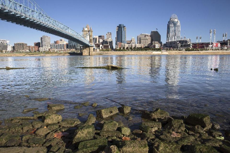 FILE – In this Oct. 16, 2015, file photo, algae coats rocks in view of Cincinnati's skyline on the banks of the Ohio River in Newport, Ky. As of early 2017, about 12,000 farmers and fertilizer applicators have completed Ohio's three-hour training program that soon will be required to use commercial fertilizer. The first-of-its-kind requirement, approved by Ohio lawmakers in 2014, is one step the state has taken to reduce farm runoff that feeds toxic algae in lakes and rivers. (AP Photo/John Minchillo, File)