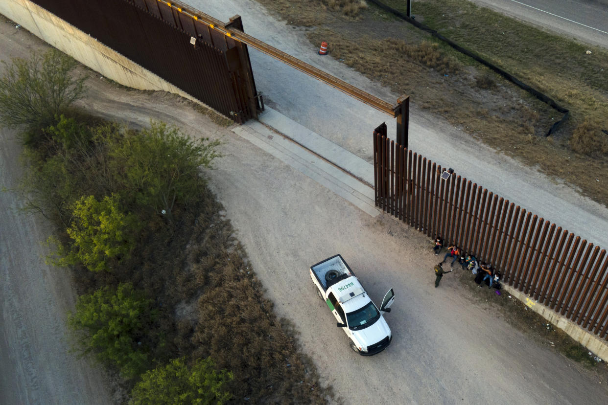 FILE - A Border Patrol agent talks to migrants after they were detained and taken into custody, March 21, 2021, in Abram-Perezville, Texas. Biden took office on Jan. 20 and almost immediately, numbers of migrants exceeded expectations. (AP Photo/Julio Cortez, File)