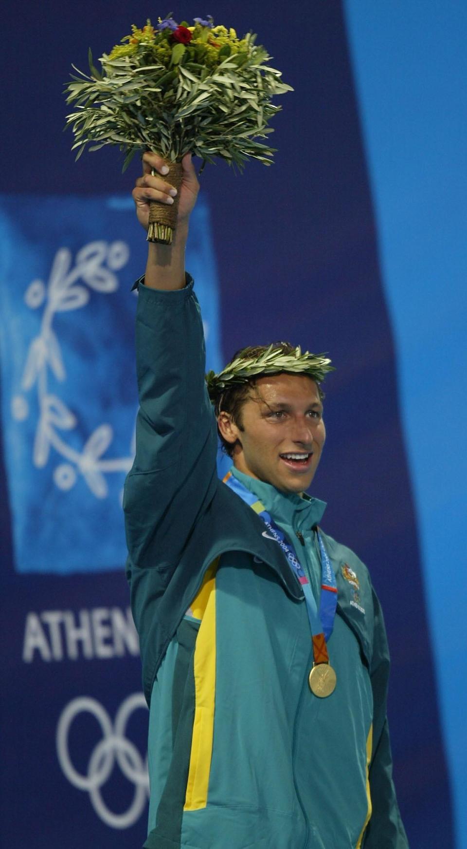 Ian wearing a medal and holding up a bouquet of flowers at the Olympics