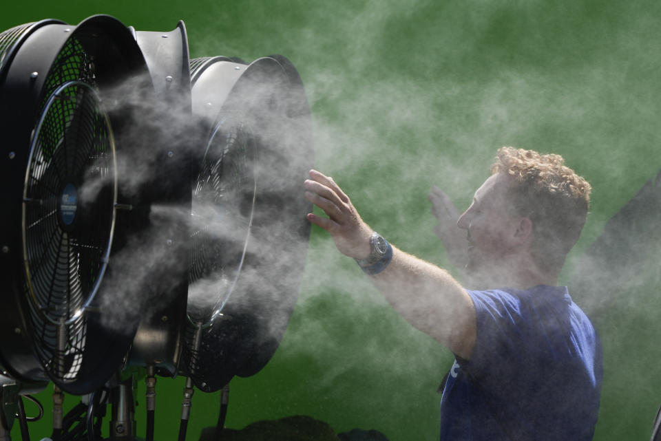 FILE - A spectator cools down during a practice day ahead of the Australian Open tennis championships at Melbourne Park, Melbourne, Australia, Jan. 12, 2024. While the U.S. is shivering through bone-chilling cold, most of the rest of world is feeling unusually warm weather. Scientists Tuesday, Jan. 16 say that fits with what climate change is doing to Earth. (AP Photo/Andy Wong, File)