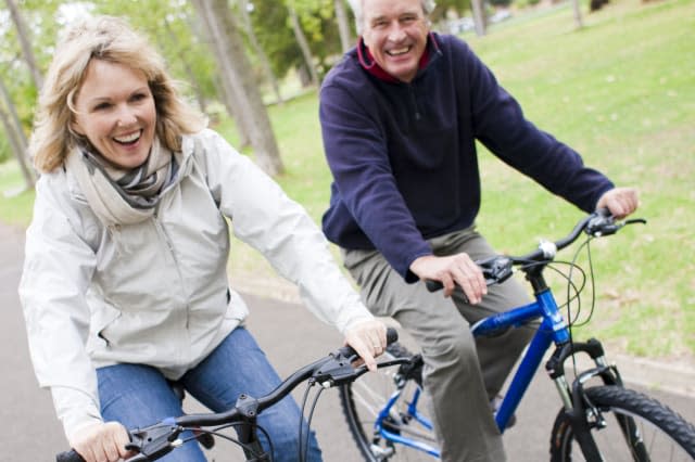 Senior couple having fun together while cycling on bikes.
