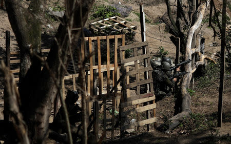 Brazilian Army soldiers take cover during a shootout with drug gangs during an operation in Alemao slums complex in Rio de Janeiro, Brazil August 20, 2018. REUTERS/Ricardo Moraes