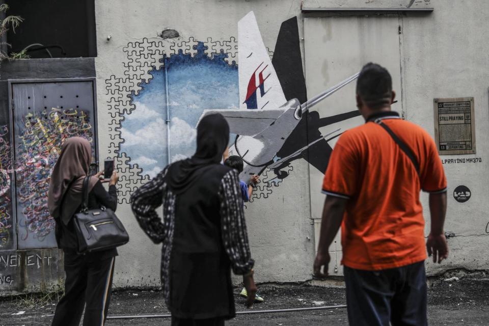 Malaysians look at the Malaysia Airlines flight MH370 mural painting at Shah Alam, outside Kuala Lumpur (EPA)