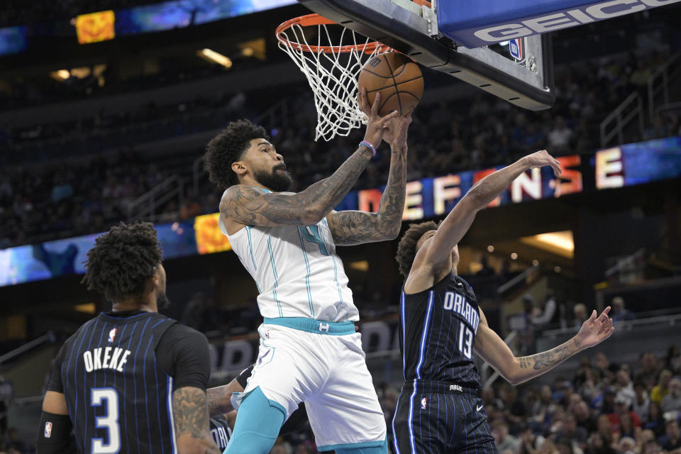 Charlotte Hornets center Nick Richards (4) grabs a rebound between Orlando Magic forward Chuma Okeke (3) and guard R.J. Hampton (13) during the first half of an NBA basketball game, Friday, Oct. 28, 2022, in Orlando, Fla. (AP Photo/Phelan M. Ebenhack)