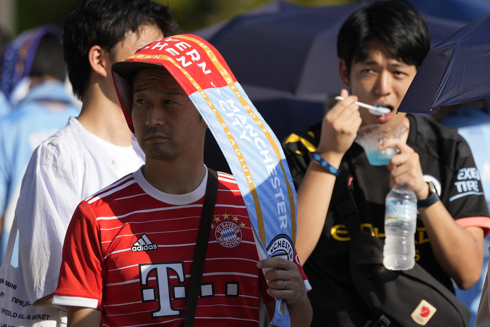 A supporter wearing a match banner to protect from the sun waits in queue to enter a venue before a friendly soccer match between Manchester City and Bayern at the National Stadium in Tokyo, Japan, Wednesday, July 26, 2023. Hot weather continues in the metro area as temperatures rise higher than 37 degrees Celsius (98.6 degrees Fahrenheit), according to Japan's meteorological bureau. (AP Photo/Shuji Kajiyama)