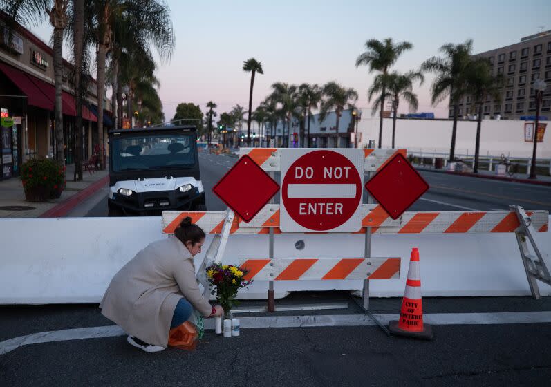 MONTEREY PARK, CA - JANUARY 22: Stephanie Kozofsky of Glendale lays flowers and electric candles at the corner of Garvey Avenue and Garfield Avenue in Monterey Park on Sunday, Jan. 22, 2023. She says this shooting was very personal because she has friends who live in Monterey Park and as a high school teacher, she has many Latino and Asian students. (Myung J. Chun / Los Angeles Times)