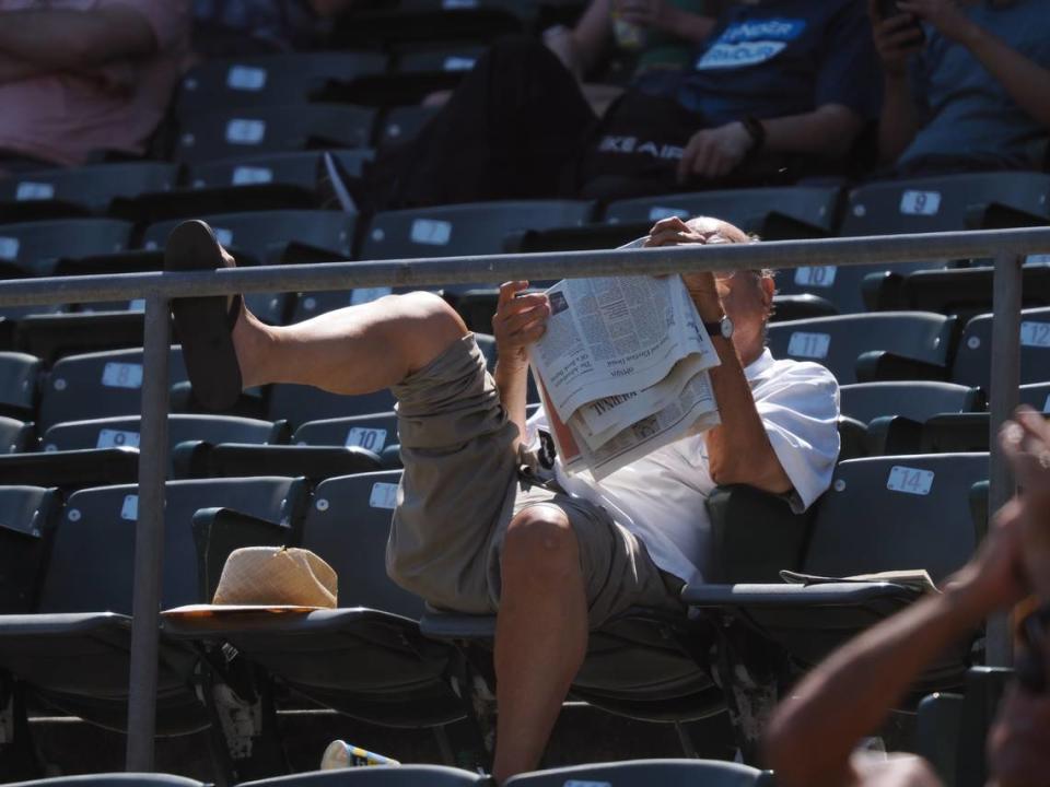A fan reads a newspaper during the eighth inning between the Oakland Athletics and Kansas City Royals at Oakland-Alameda County Coliseum.