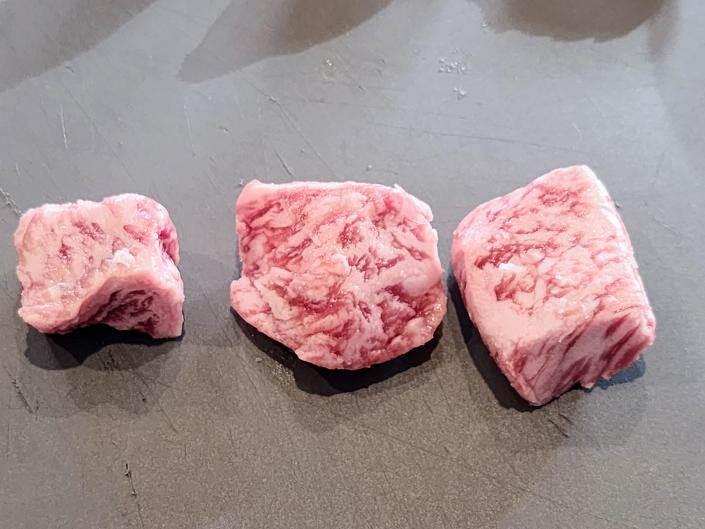 three raw cubes of wagyu steak on a kitchen counter