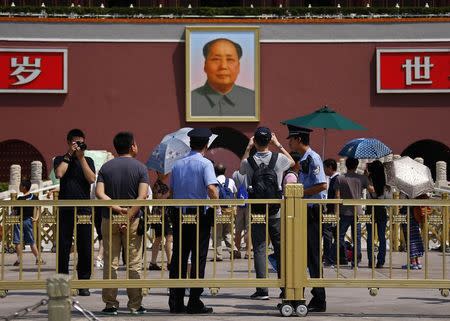 Policemen watch as tourists take pictures in front of the Tiananmen Gate, in Beijing, June 3, 2014. REUTERS/Petar Kujundzic