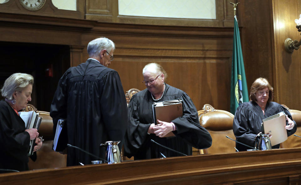 Washington Supreme Court Justice Susan Owens, left, Justice Charles W. Johnson, Chief Justice Mary E. Fairhurst and Justice Barbara A. Madsen stand up to leave the court at the conclusion of a hearing there about public records Tuesday, June 11, 2019, in Olympia, Wash. The court heard oral arguments in the case that will determine whether state lawmakers are subject to the same disclosure rules that apply to other elected officials under the voter-approved Public Records Act. The hearing before the high court was an appeal of a case that was sparked by a September 2017 lawsuit filed by a media coalition, led by The Associated Press. (AP Photo/Elaine Thompson)