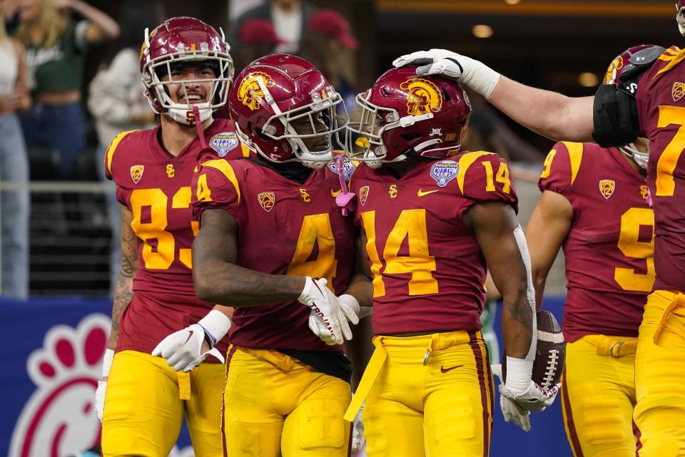 Southern California running back Raleek Brown (14) is congratulated by teammates after scoring a touchdown during the first half of the Cotton Bowl NCAA college football game against Tulane, Monday, Jan. 2, 2023, in Arlington, Texas. (AP Photo/Sam Hodde)