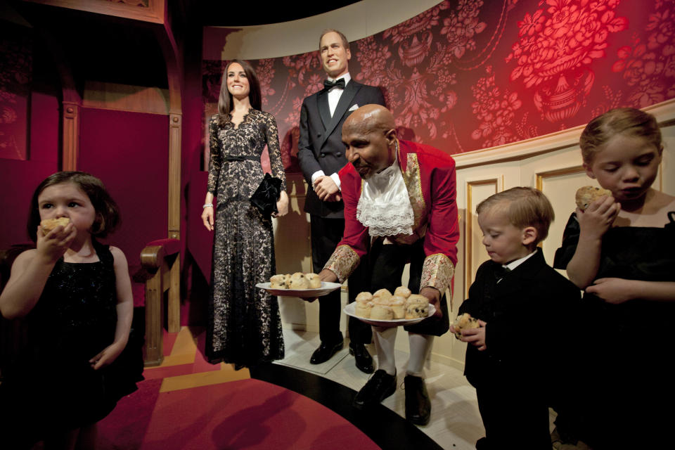 Child models eat scones as they pose with waxworks of Britain's Royal couple William and Catherine, the Duke and Duchess of Cambridge, at Madame Tussauds in Amsterdam, Netherlands, Wednesday, April 4, 2012. Madame Tussauds Amsterdam captures the Duchess' recent appearance at the War Horse premiere where she wore a lace Alice Temperley number. (AP Photo/Peter Dejong)