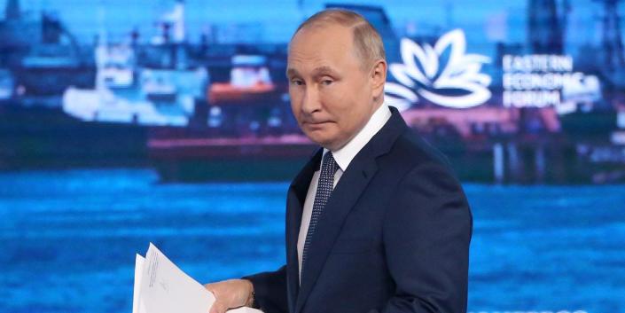 Vladimir Putin holding papers and walking at a conference