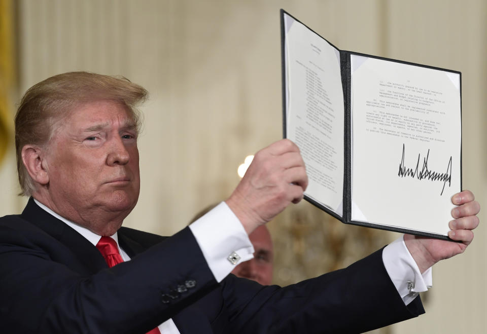 President Trump holds up the space policy directive that he signed during a National Space Council meeting in the East Room of the White House in Washington. (AP Photo/Susan Walsh)