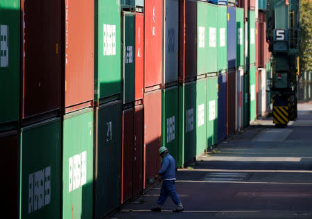 FILE PHOTO: A worker walks between shipping containers at a port in Tokyo, Japan, March 22, 2017. REUTERS/Issei Kato/File Photo