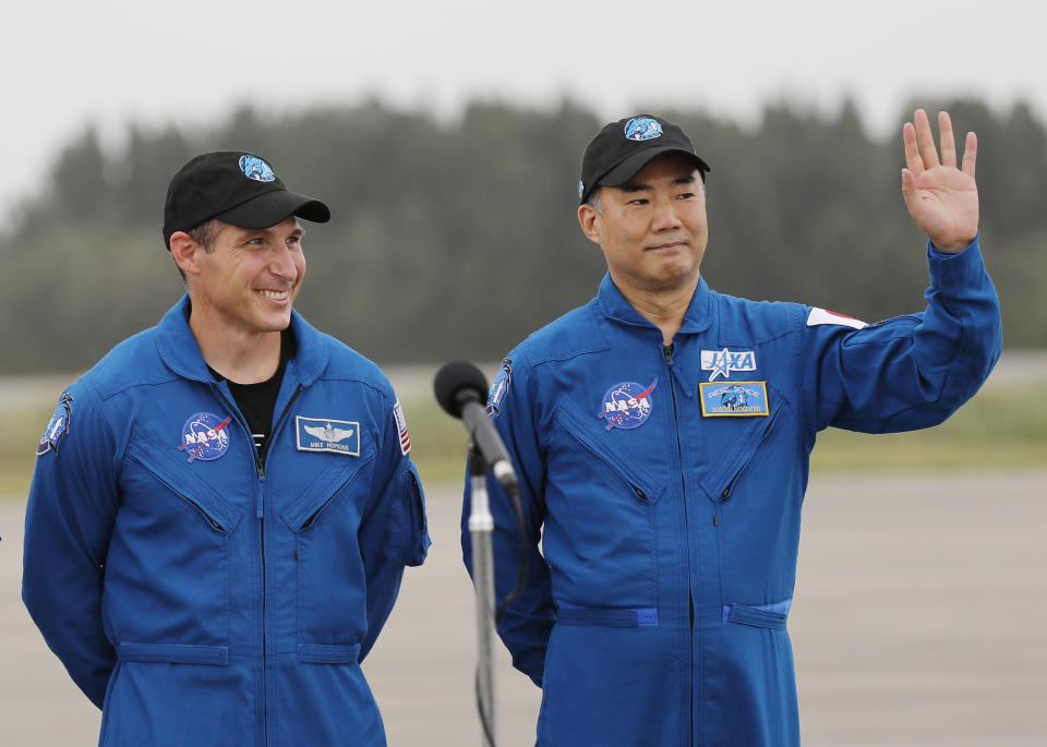 Astronaut Soichi Noguchi, right, of Japan, waves to the media as NASA Astronaut Michael Hopkins looks on during a news conference after they arrived at Kennedy Space Center, Sunday, Nov. 8, 2020, in Cape Canaveral, Fla. Four astronauts will fly on the SpaceX Crew-1 mission to the International Space Station scheduled for launch on Nov. 14, 2020. (AP Photo/Terry Renna)