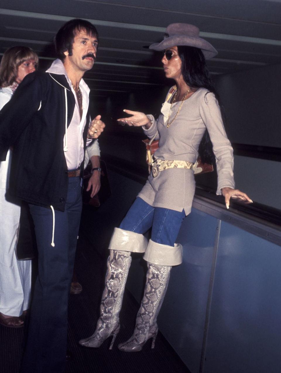 <p>Arriving to the airport in a cowboy hat and snake print over-the-knee boots with Sonny. </p>