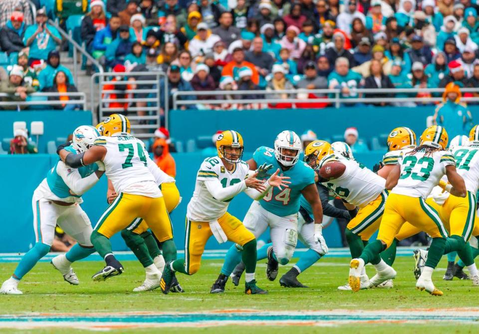 Green Bay Packers quarterback Aaron Rodgers (12) toss the football to Packers running back Aaron Jones (33) during third quarter of an NFL football game against the Miami Dolphins at Hard Rock Stadium on Sunday, December 25, 2022 in Miami Gardens, Florida.