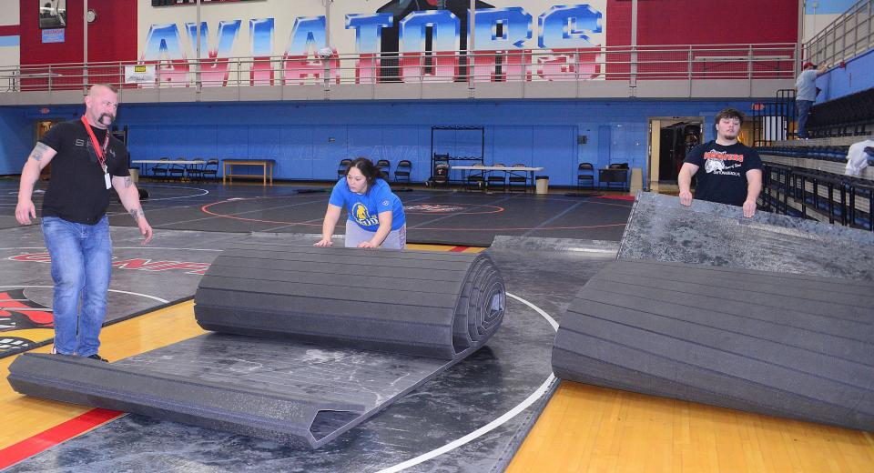 Isabella Hall, center, and Dane Johnson assist Dave Pennington, left, during the setup for the 2024 Top Gun Tournament on Thursday, Jan. 11, 2024, in the Alliance High School gymnasium.