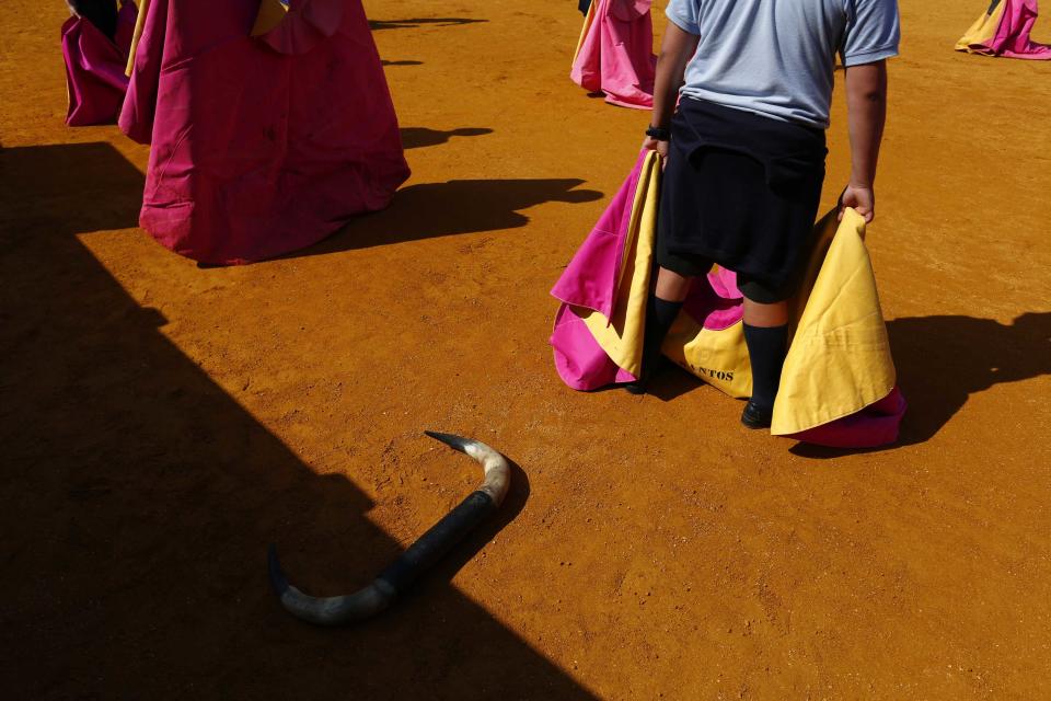 Students hold capotes during a bullfight master class for schoolchildren at the Maestranza bullring in the Andalusian capital of Seville, southern Spain, April 23, 2014.