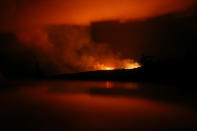 <p>The latest Kilauea volcano activity illuminates the sky and is reflected off a vehicle (Bottom) on Hawaii’s Big Island on May 14, 2018 in Pahoa, Hawaii. (Photo: Mario Tama/Getty Images) </p>