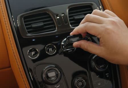 Sales Manager Raymond Liu starts the engine of an Aston Martin Vanquish with a unique glass key at their showroom in Singapore August 1, 2014. REUTERS/Edgar Su