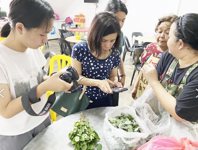 為了完成計畫，陳翎(左)拍攝600多張母國野菜等菜餚照片。（圖／移民署提供）