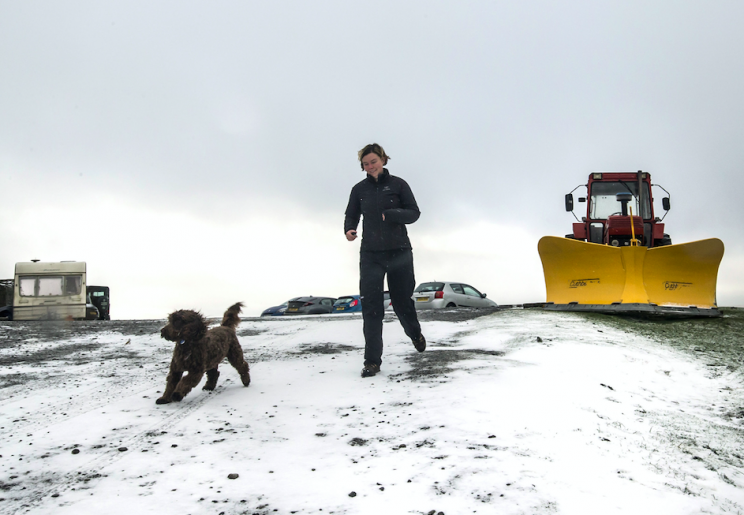 A woman walks her dog in the snow at Tan Hill in North Yorkshire (Picture: PA)