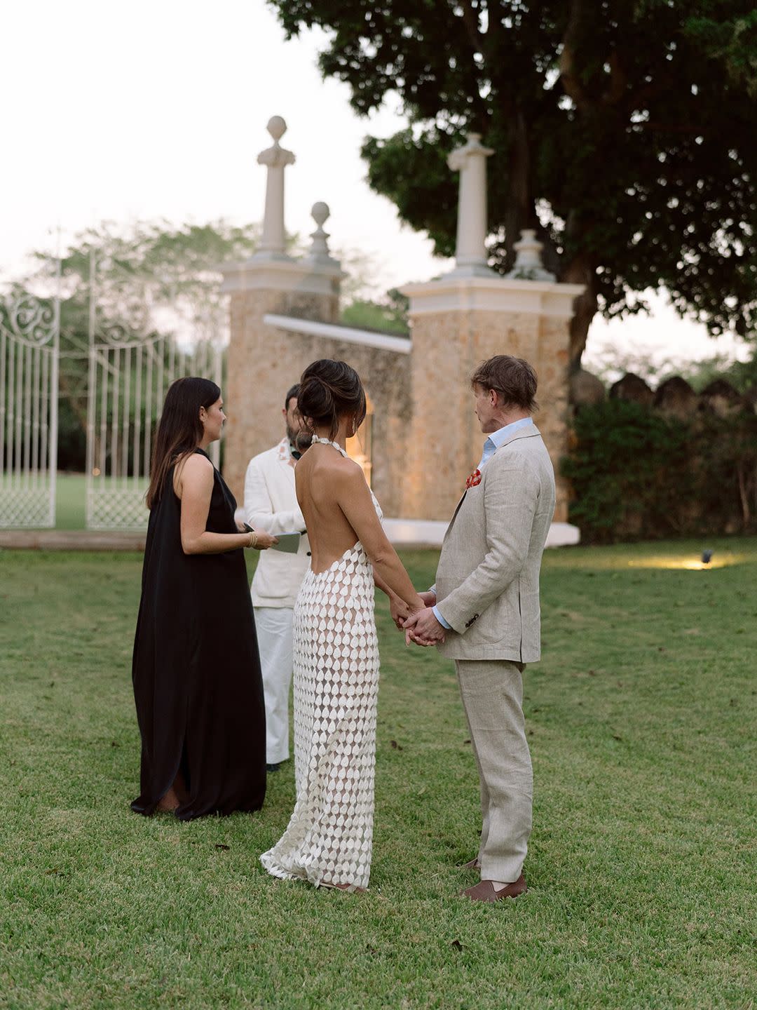 a group of people standing in a grassy area with a statue in the background