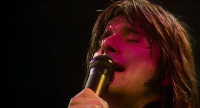 A man sings passionately into a microphone he's holding