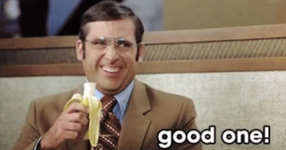 Steve Carell in a suit, holding a banana and laughing while saying "good one!"