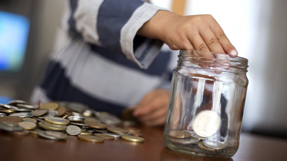 Niño metiendo monedas en un bote de cristal