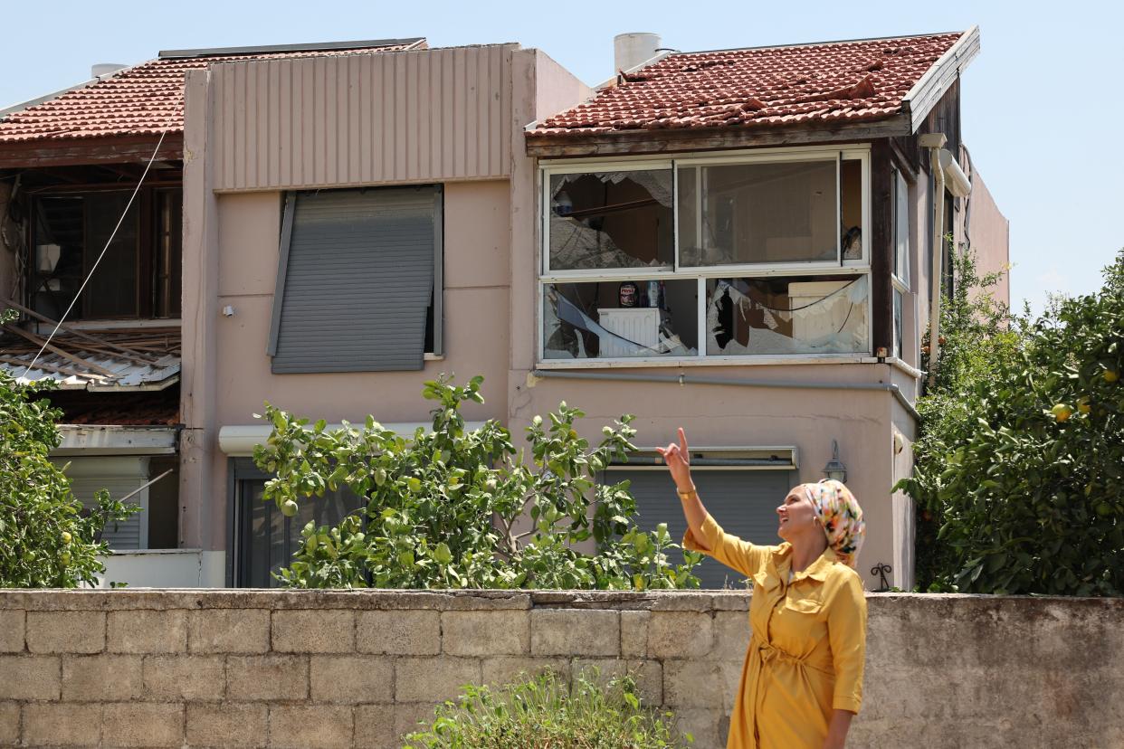 A resident stands next to a house damaged by a rocket fired from Lebanon in the Israeli coastal town of Acre (AFP via Getty Images)