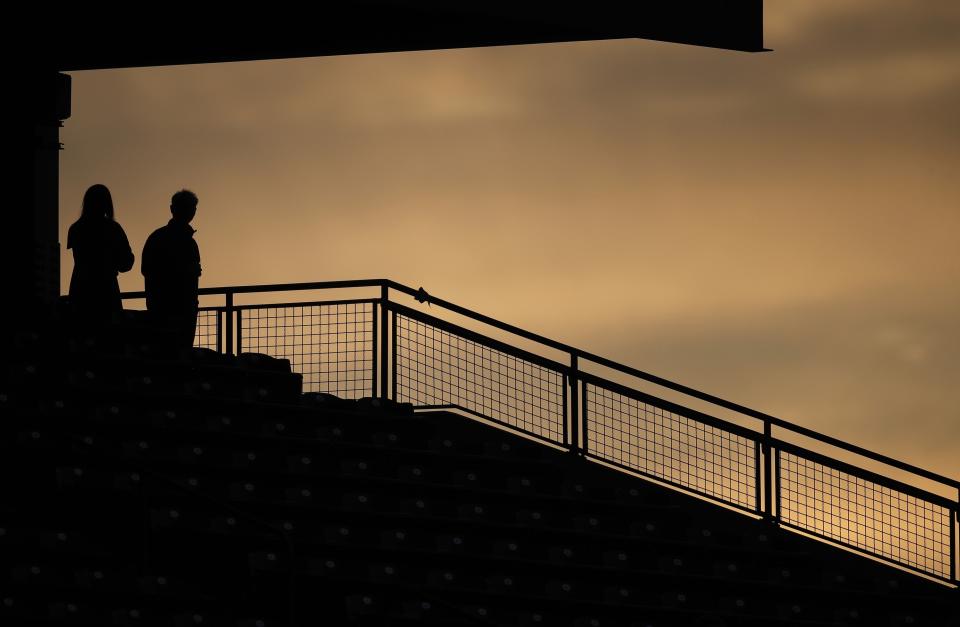 Two fans are silhouetted against the sky near sunset, during the fourth inning of a baseball game between the San Diego Padres and the Colorado Rockies on Friday, May 10, 2019, in Denver. (AP Photo/David Zalubowski)