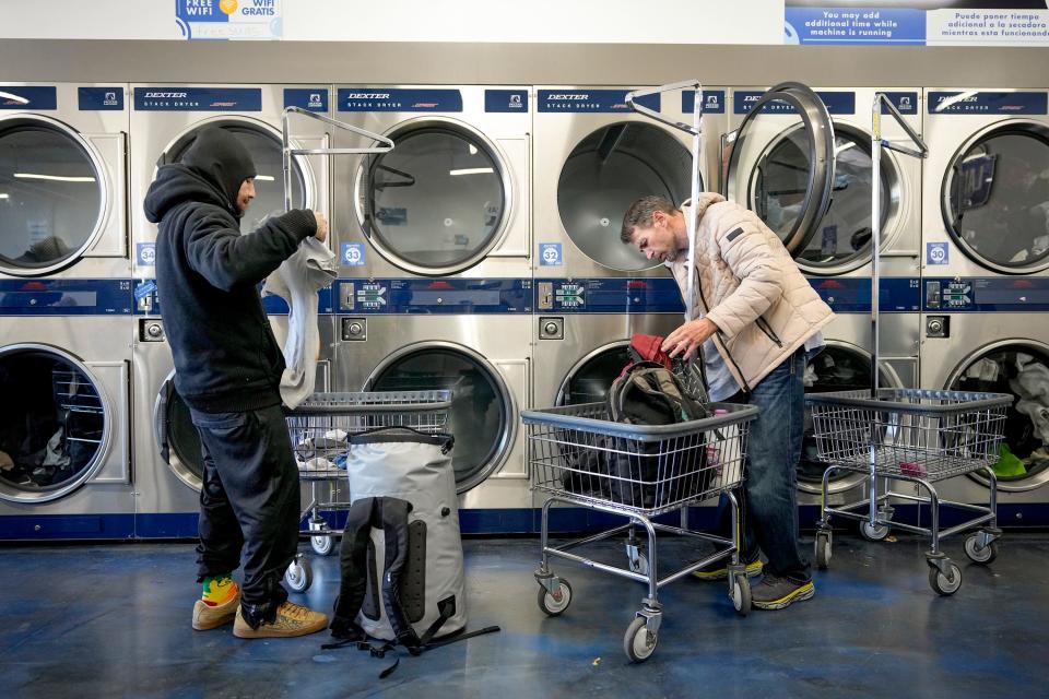 Jesse Peña, left, and Michael Vons do their laundry at Clean Laundry laundromat last Monday. Maximizing Hope began in 2020 with outreach efforts to encampments under highway overpasses, but it then shifted to laundromat-based events in 2021 as the camping ban pushed those without housing deep into the woods.