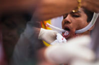 PHUKET, THAILAND - OCTOBER 05: A devotee of the Chinese shrine of Sui Boon Tong Shrine, pierces his cheeks with rubber tube during a procession of Vegetarian Festival on October 5, 2011 in Phuket, Thailand. Ritual Vegetarianism in Phuket Island traces it roots back to the early 1800's. The festival begins on the first evening of the ninth lunar month and lasts for nine days. Participants in the festival perform acts of body piercing as a means of shifting evil spirits from individuals onto themselves and bring the community good luck. (Photo by Athit Perawongmetha/Getty Images)