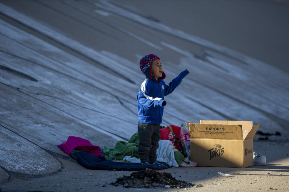 A migrant child cries to get the attention of his father while the family waits in the southern bank of the Rio Grande to cross into El Paso, Texas from Ciudad Juarez, Mexico, on Wednesday, Dec. 21, 2022. (AP Photo/Andres Leighton)