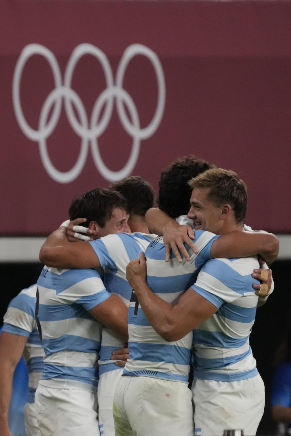 Argentina players, including Argentina's Santiago Mare, right, embrace as they celebrate defeating South Africa in their men's rugby sevens quarterfinal match at the 2020 Summer Olympics, Tuesday, July 27, 2021 in Tokyo, Japan. (AP Photo/Shuji Kajiyama)