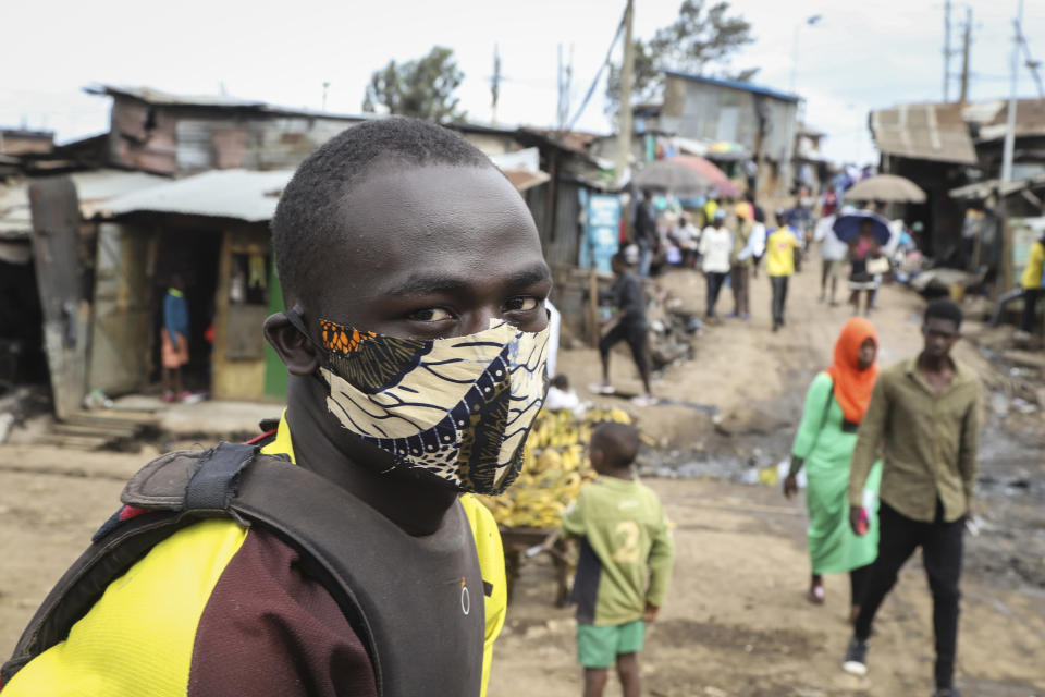 A boda-boda, or motorcycle taxi, driver wears a makeshift mask made from a local fabric known as Kitenge as he looks for customers in the Kibera neighbourhood of Nairobi, Kenya Friday, March 20, 2020. For most people, the new coronavirus causes only mild or moderate symptoms such as fever and cough and the vast majority recover in 2-6 weeks but for some, especially older adults and people with existing health issues, the virus that causes COVID-19 can result in more severe illness, including pneumonia. (AP Photo/Patrick Ngugi)