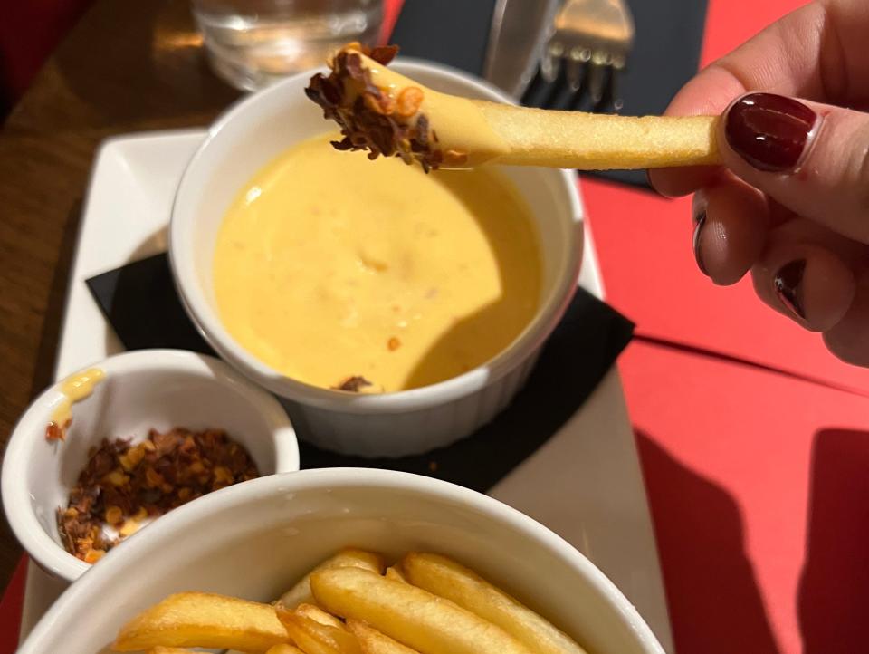 A french fry dipped in cheese and covered with chili flakes.