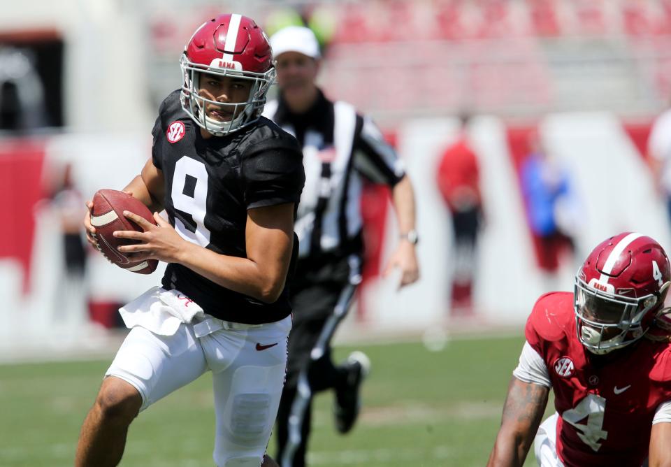 Quarterback Bryce Young (9) scrambles for a first down after moving away from Crimson linebacker Christopher Allen (4) during the Alabama A-Day game.