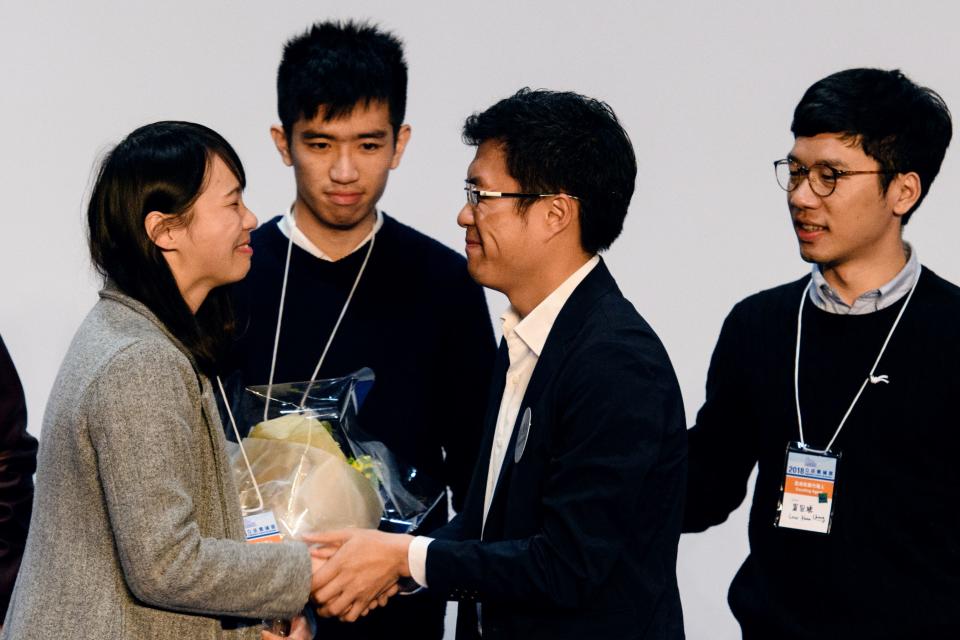 Pro-democracy candidate Au Nok-hin (C) is congratulated by disqualified lawmaker Nathan Law (R) and disqualified candidate Agnes Chow (L) after Au won the Legislative Council by-election for the Hong Kong Island constituency on March 12, 2018.