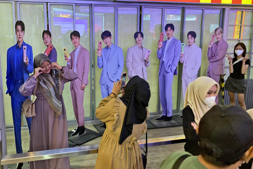 Fans take photos with cardboard cutouts of members of South Korean boy band Exo at a shopping mall in Jakarta, Indonesia, Sunday, Feb. 4, 2024. As Indonesia votes this month to replace popular President Joko Widodo, all three candidates have all been aggressively seeking to win the votes of younger people, reaching out to them on the apps they use, through the K-pop music many love, and even video gaming events. (AP Photo/Dita Alangkara)