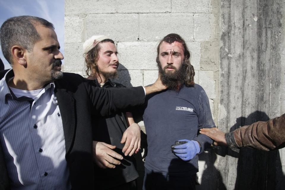 Palestinians hold injured Israeli settlers detained by Palestinian villagers near the West Bank village of Qusra, southeast of the city of Nablus, Jan. 7, 2014. (AP Photo/Nasser Ishtayeh)