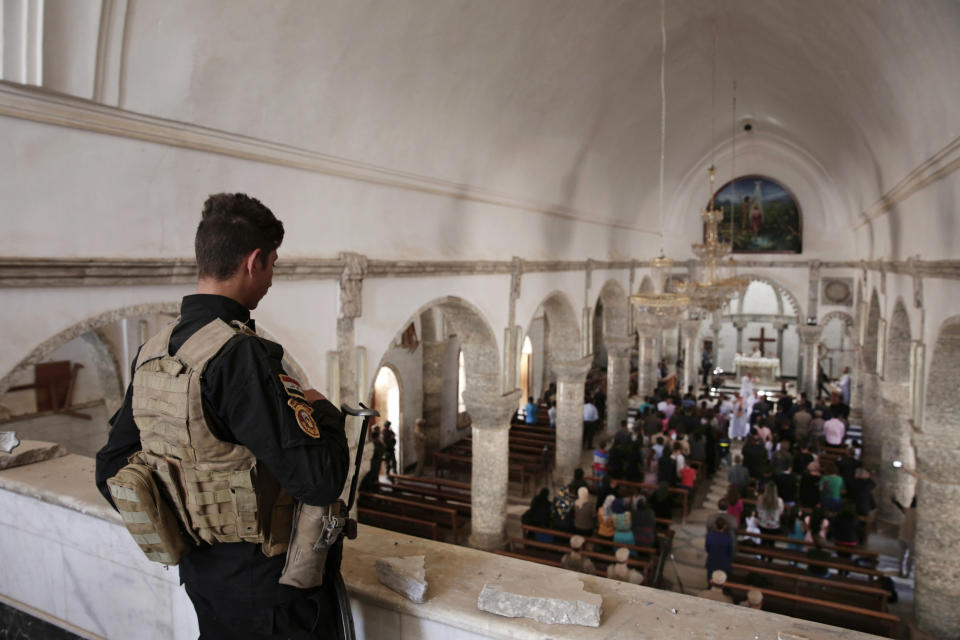 In this April 16, 2017, photo a Christian militiaman stands guard during Easter mass in Qaraqosh, Iraq. Synagogues, mosques, churches and other houses of worship are routinely at risk of attack in many parts of the world. And so worshippers themselves often feel the need for visible, tangible protection even as they seek the divine. (AP Photo/Maya Alleruzzo)