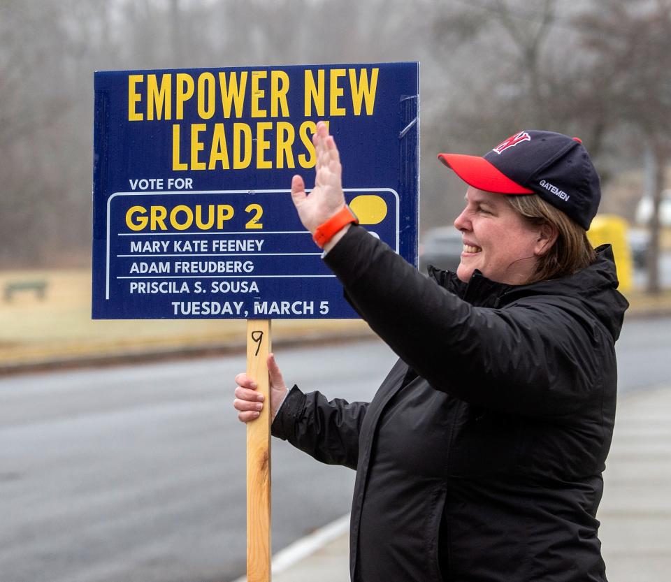 Mary Kate Feeney, a candidate for the Group 2 slate for Framingham Democratic Committee, waves to passing vehicles while standing outside the Brophy Elementary School on Tuesday, March 5, 2024.