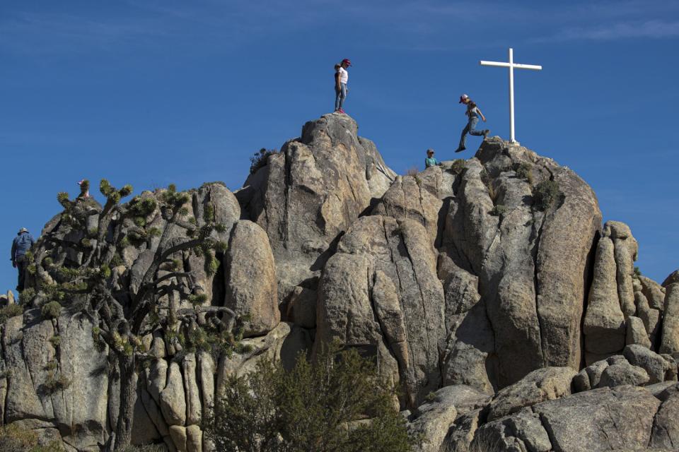 A white cross and children on a rocky terrain.