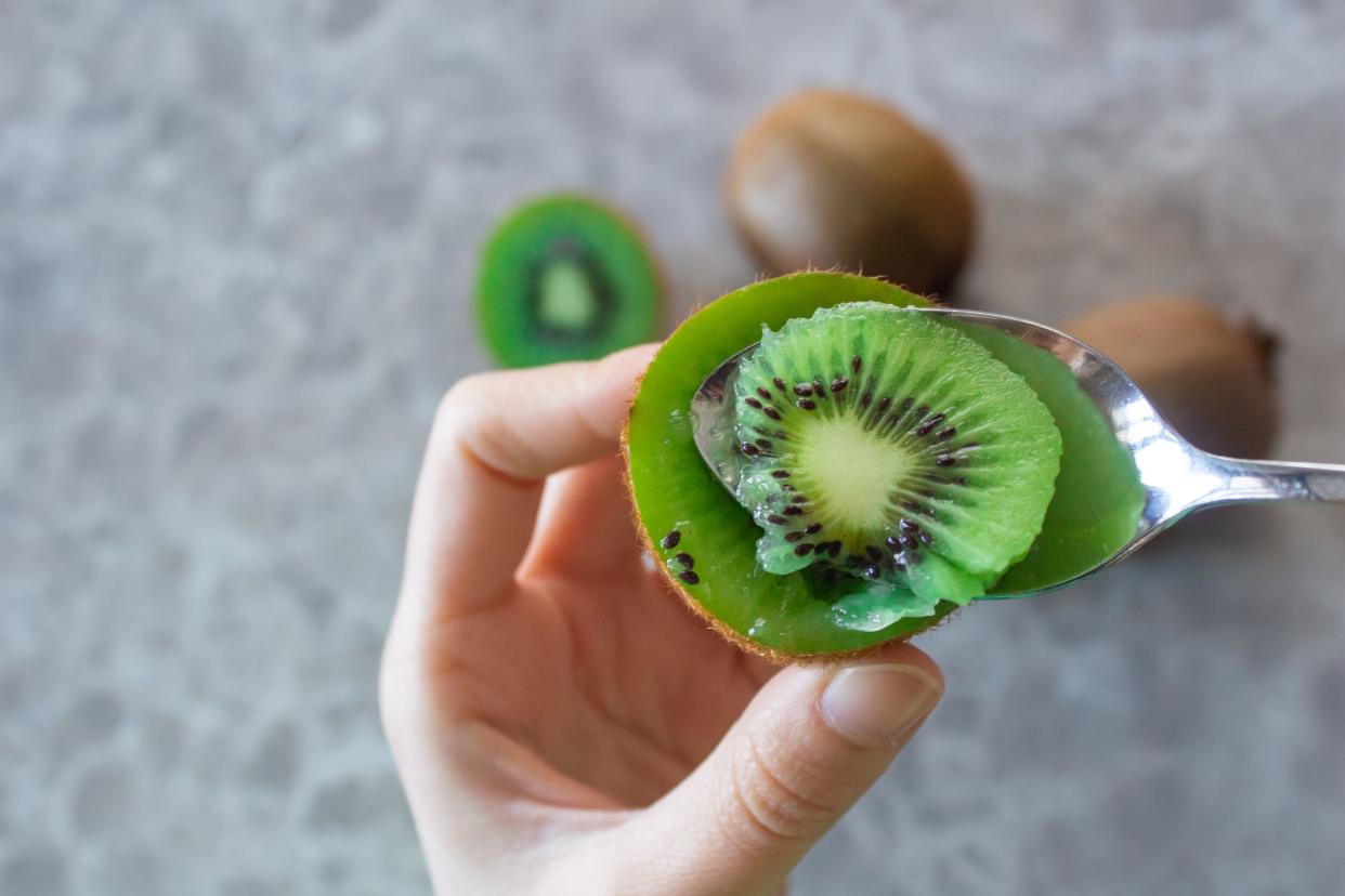 Woman eating kiwi fruit. Healthy lifestyle concept. Top view, closeup photo.