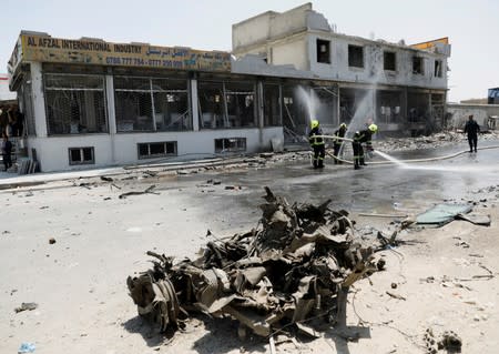 Afghan firefighters wash the road after a blast in Kabul, Afghanistan