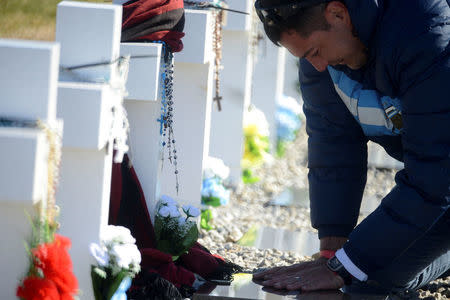 A relative of an Argentine soldier who died during the Falklands War touches his tombstone at Darwin cemetery, in the Falkland Islands, March 26, 2018. Argentine Presidency/Handout via REUTERS